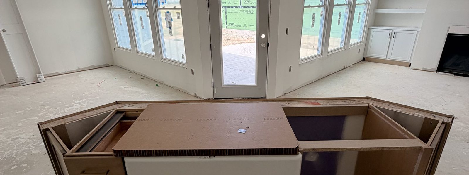 Large kitchen island set under bay windows before countertops