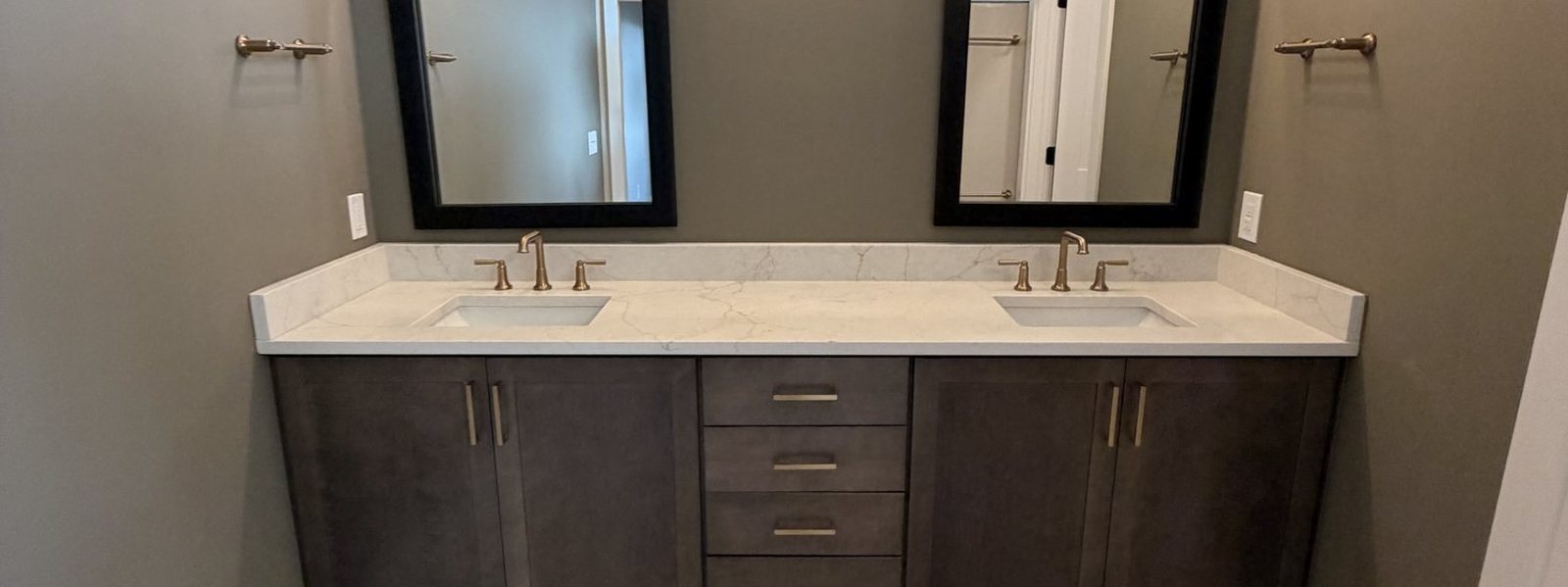 Finished bathroom with a dark double vanity, twin mirrors and marble-look tile floor