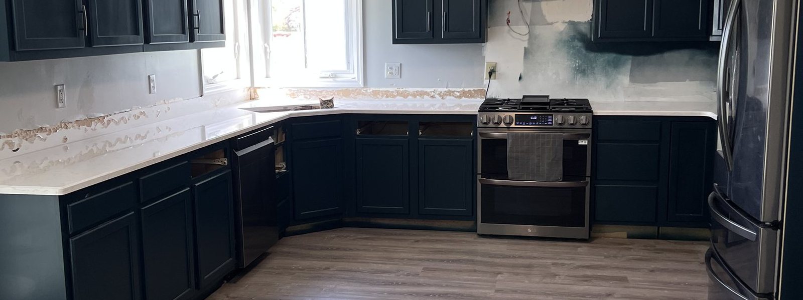 Finished kitchen in navy cabinetry with white countertops and a stainless range
