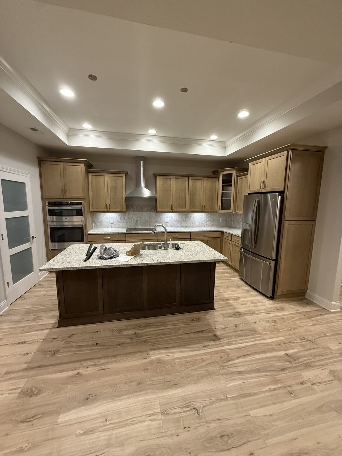 Finished walnut kitchen with island sink, stainless hood and double wall ovens