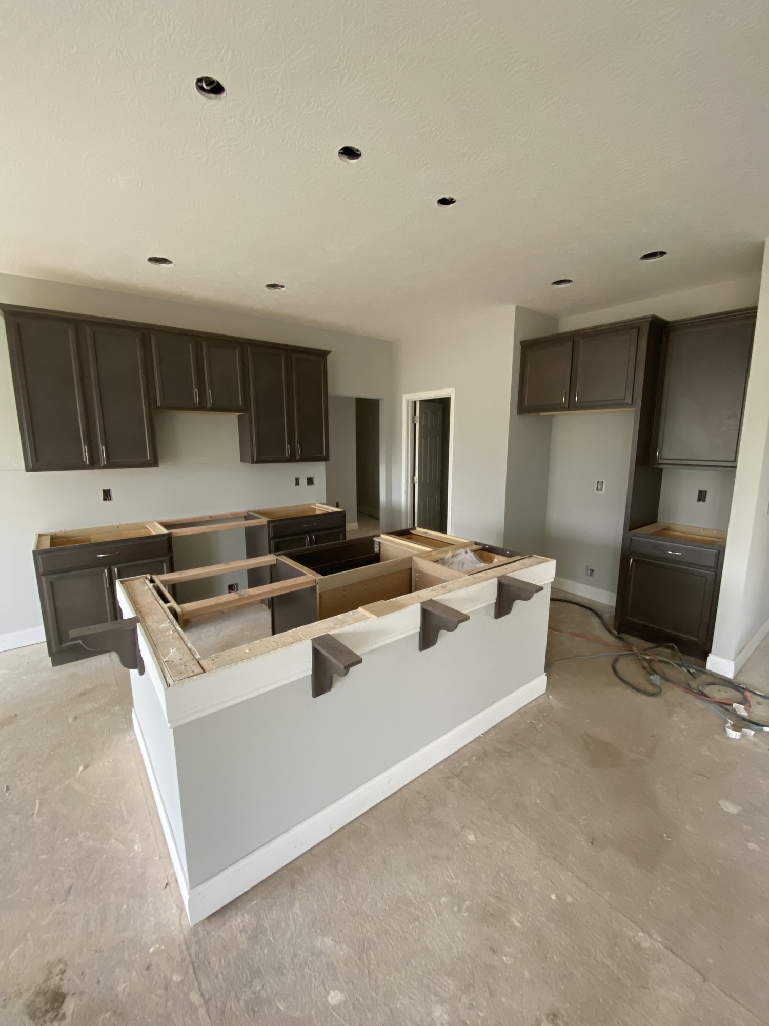 Dark cabinetry set with island framing in place mid-install