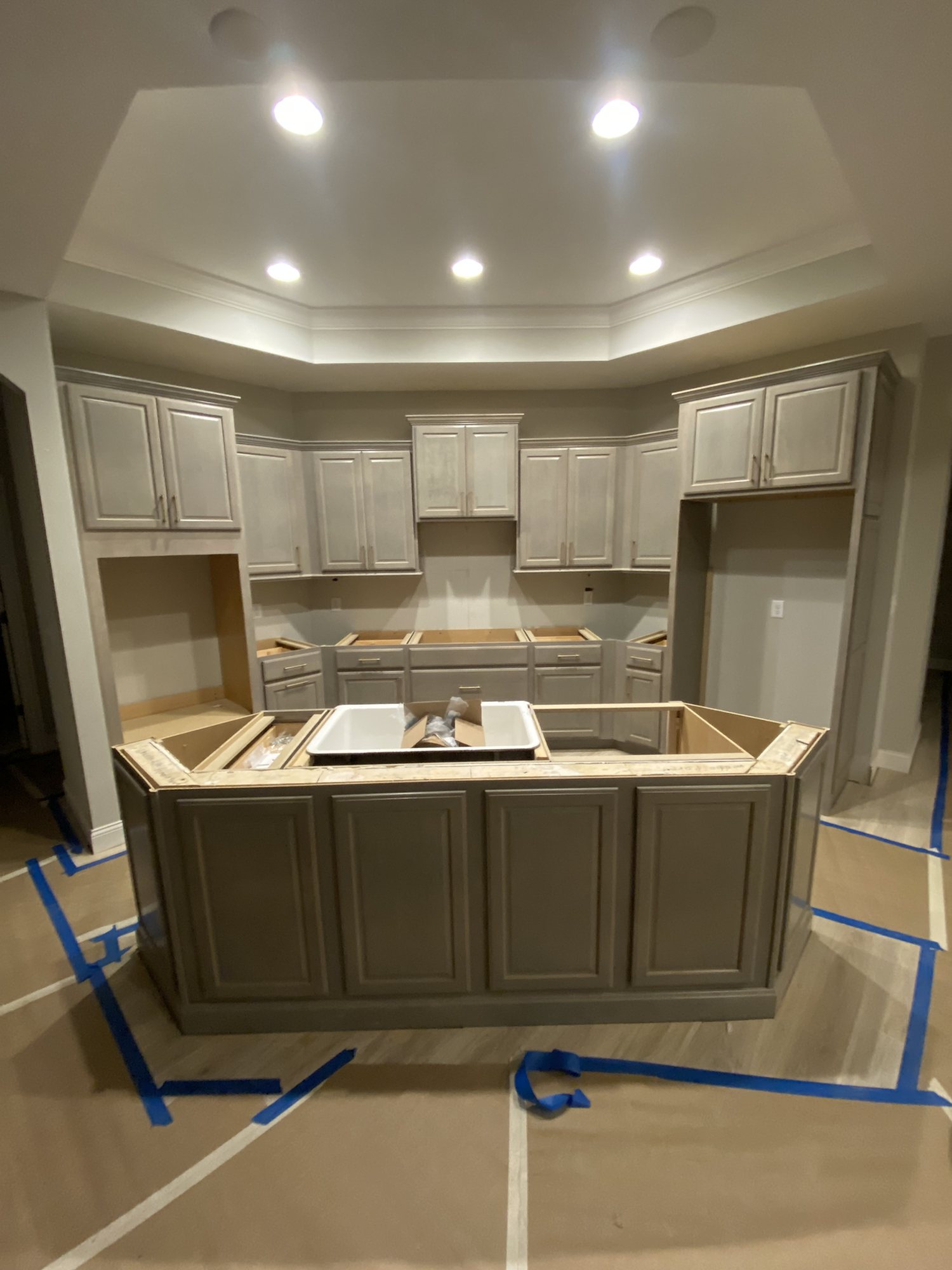 Greige cabinetry with crown moulding set under a tray ceiling