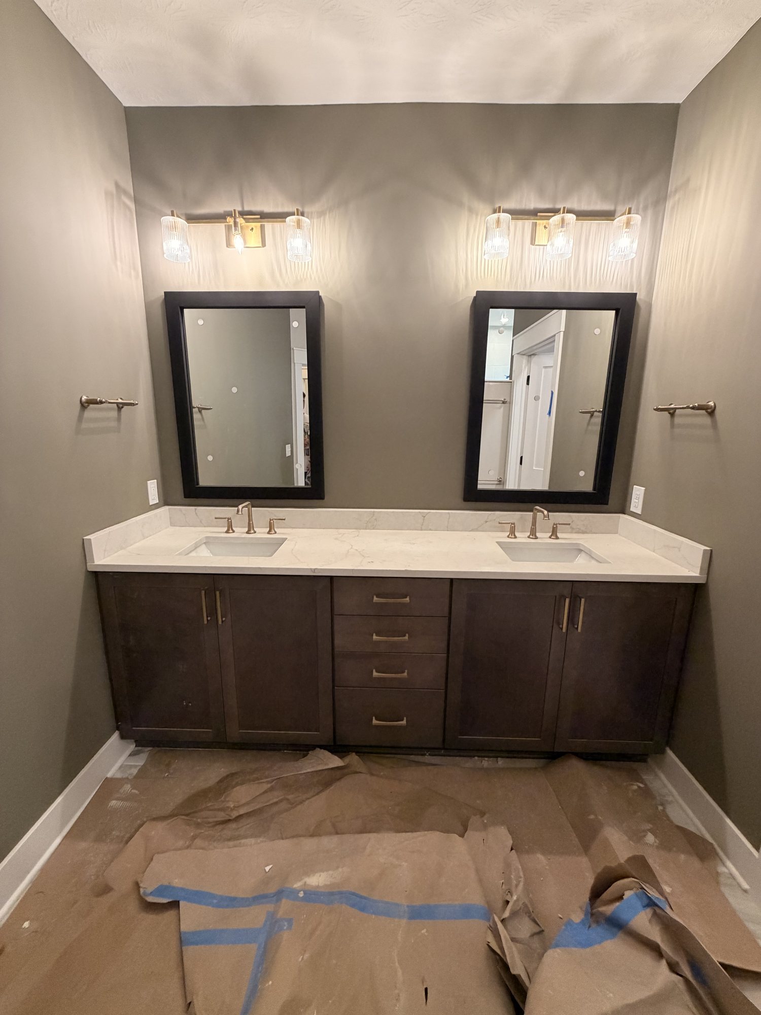 Bathroom double vanity in dark cabinetry with a white top and twin mirrors