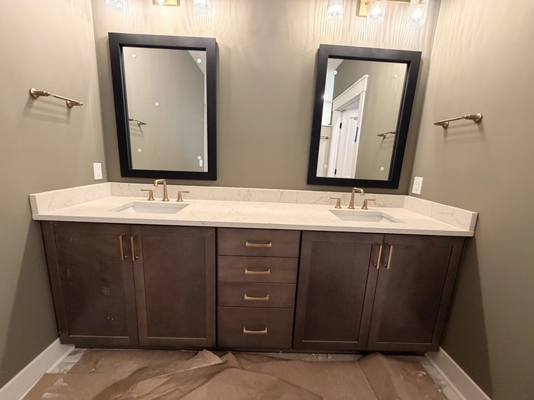 Finished bathroom with a dark double vanity, white countertop and brass fittings
