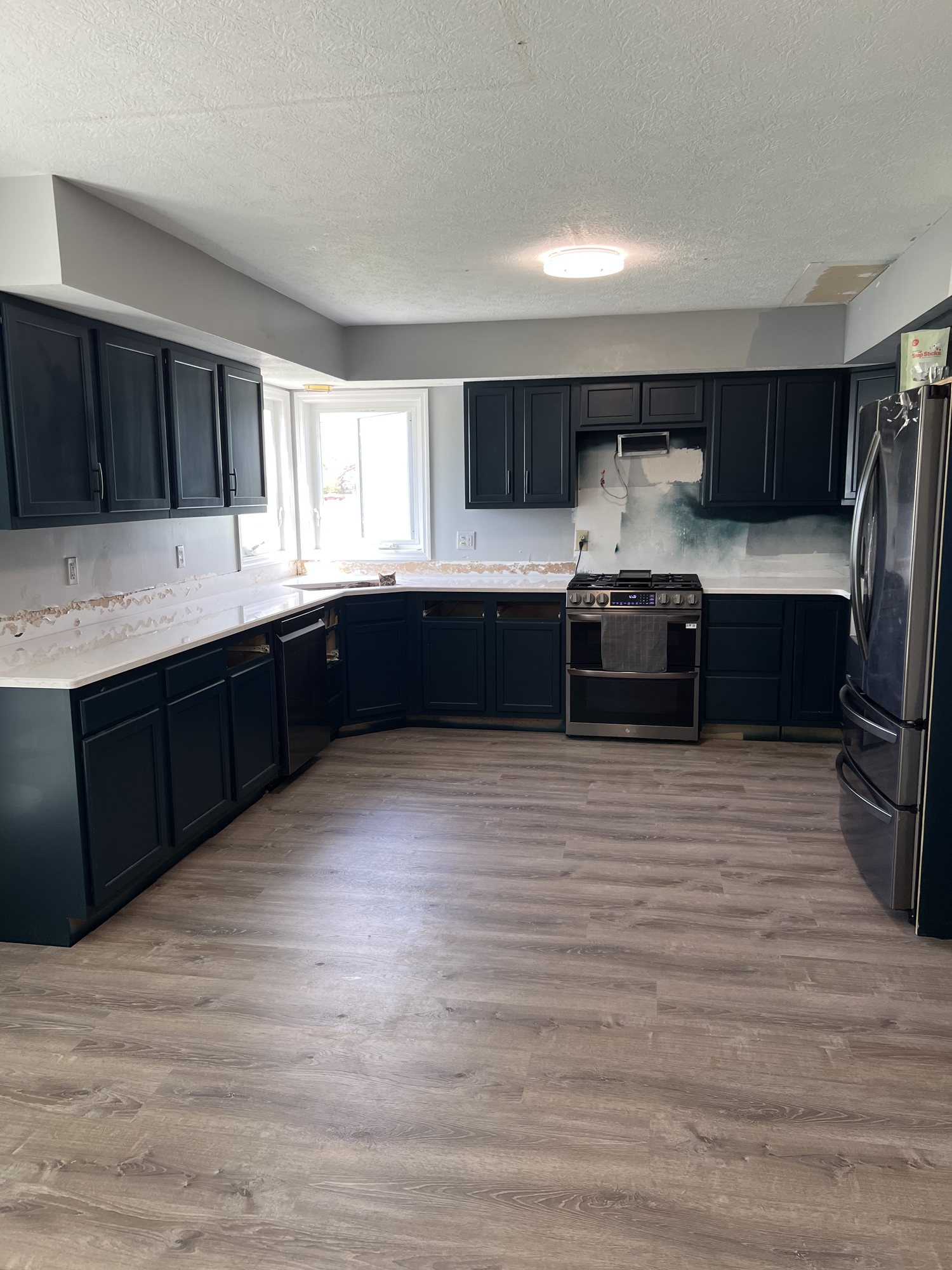 Completed kitchen in navy cabinetry with white countertops, stainless range and refrigerator