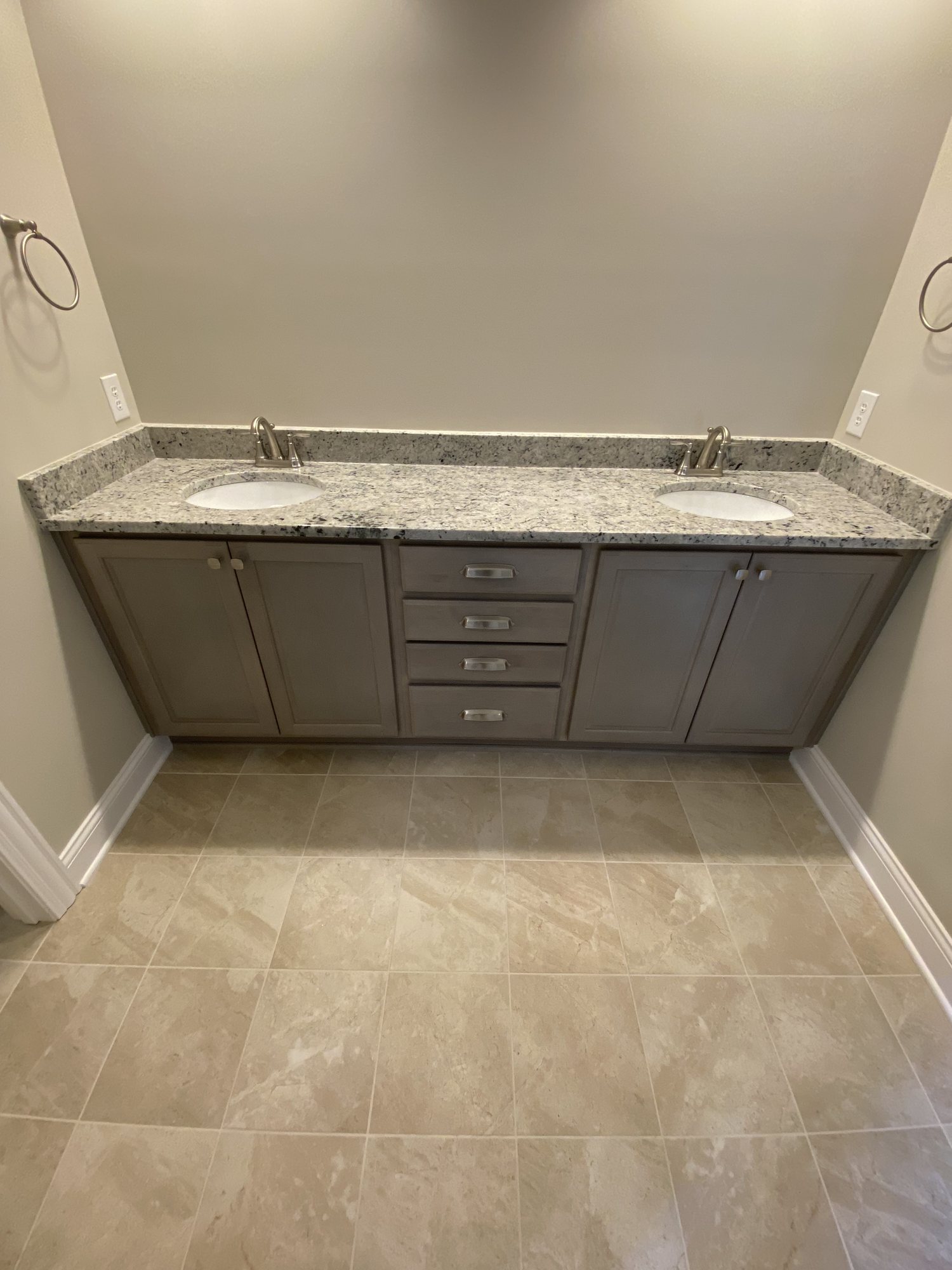 Finished bathroom with a double vanity, granite top, undermount sinks and tiled floor