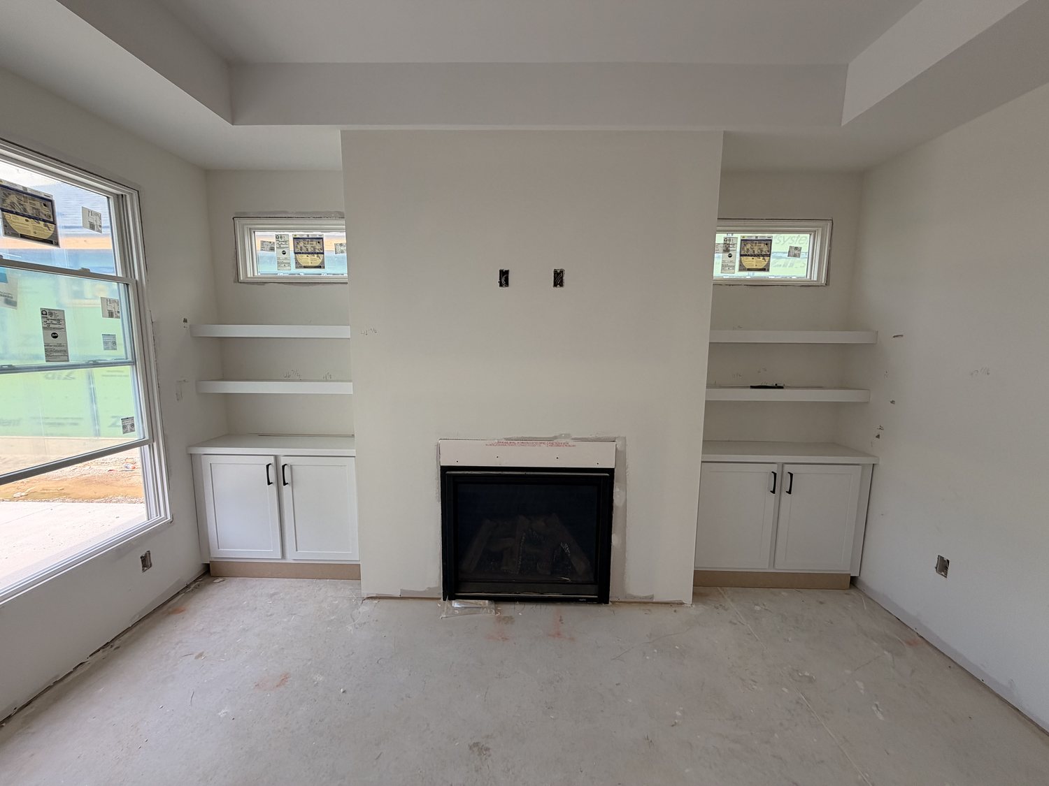 Fireplace flanked by white built-in cabinetry and shelving