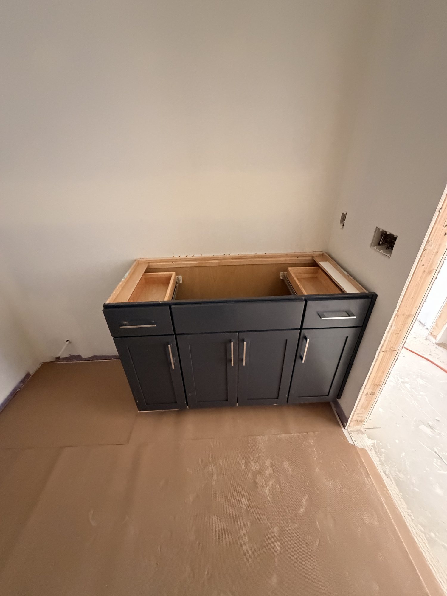 Bathroom vanity in dark cabinetry, set and ready for its top